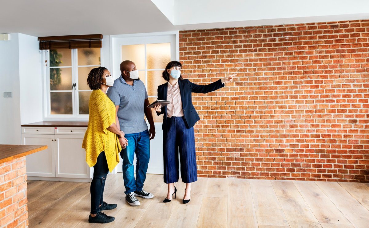 Real estate agent and customer in face mask looking at a new project