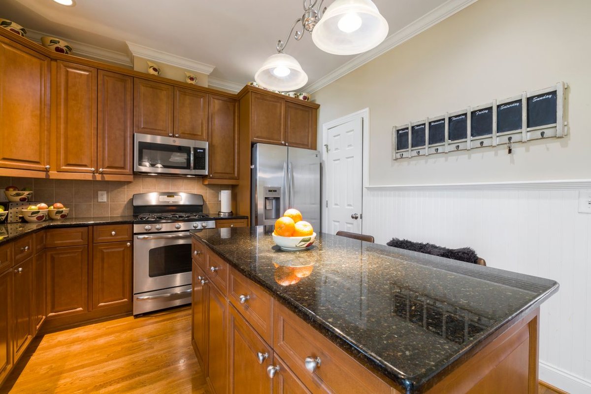 Bright kitchen featuring granite countertops, wooden cabinets, and stainless steel appliances.