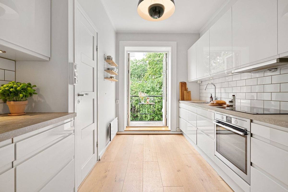 A sleek modern kitchen with white cabinets and access to a small balcony