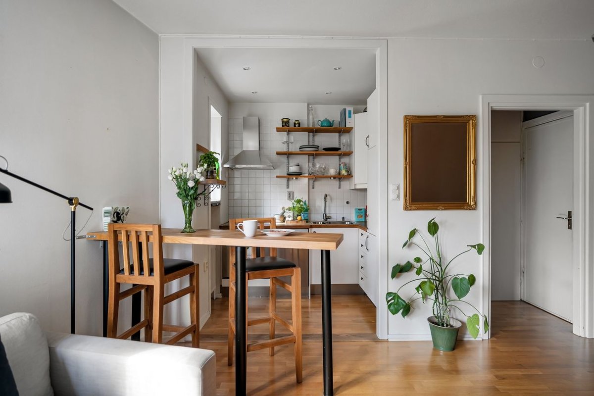 A cozy kitchen and dining area with wooden furniture and green plants creating a modern Scandinavian design.