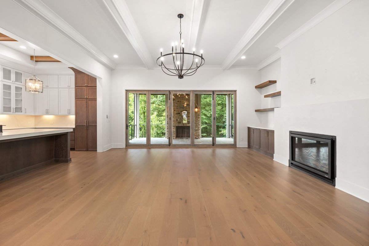 Contemporary living room featuring hardwood floors, chandelier, and open kitchen layout.