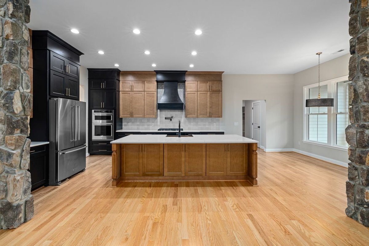 Elegant modern kitchen featuring a spacious island, stainless appliances, and stylish cabinetry under warm lighting.