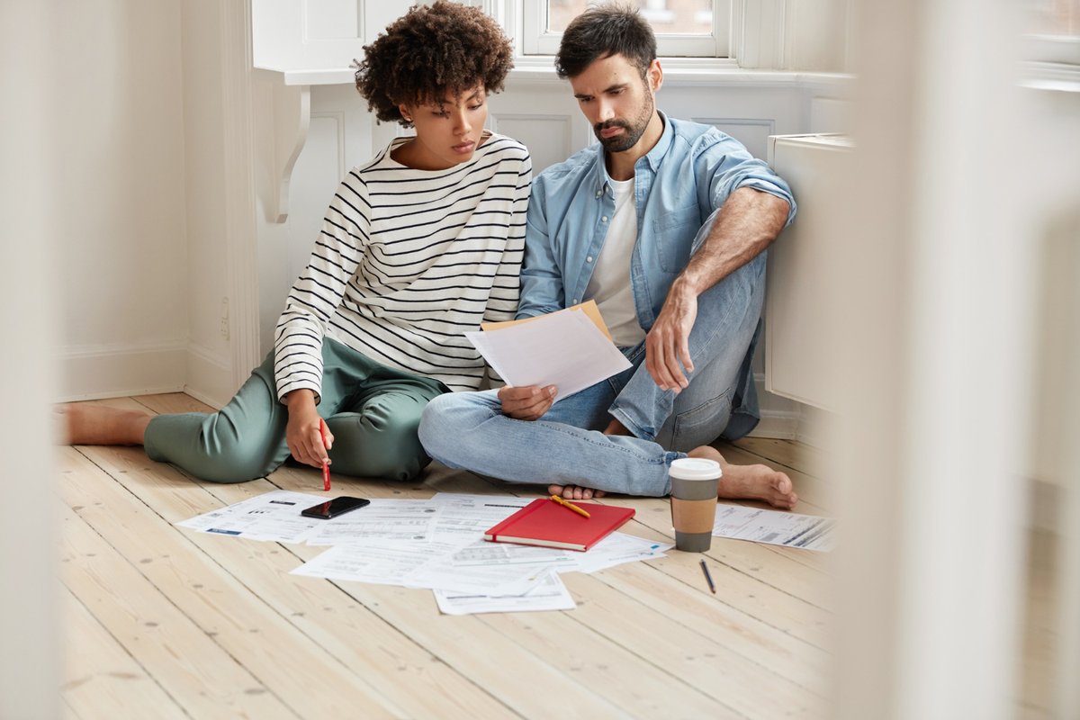 Man and woman sitting on the floor together while reading a contract
