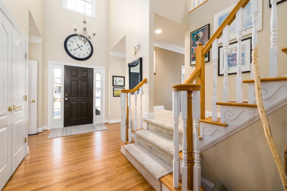 A bright and spacious modern entrance hall featuring a large clock and elegant staircase.