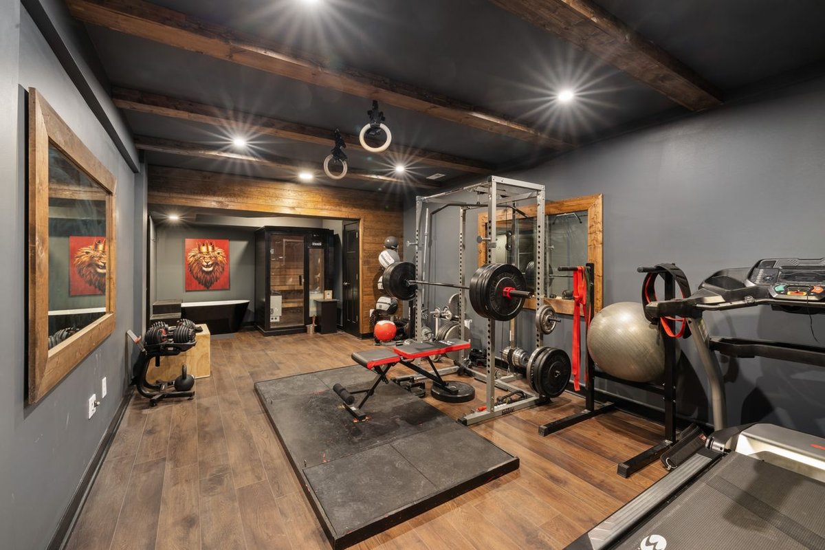 A basement converted into a home gym with gym equipment and laminated flooring