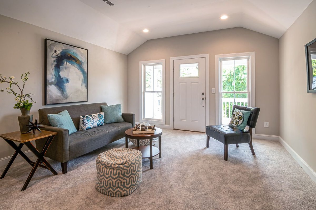 A cozy living room with gray carpet and open big windows