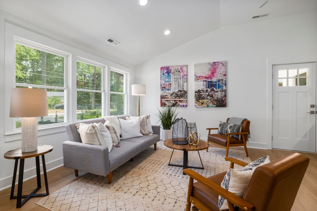 A cozy living room with big open windows and carpet as flooring