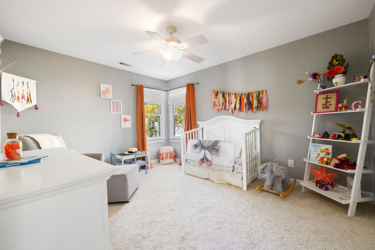 A spacious nursery room featuring a crib, playful decor, and bright natural light.
