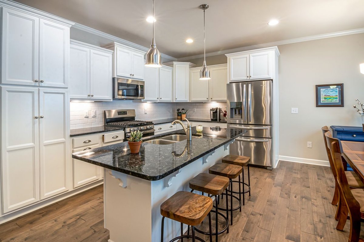 Elegant modern kitchen featuring white cabinets and a black marble island.