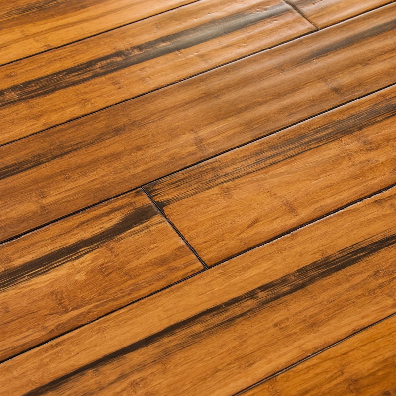 Close-up of a wooden floor with medium-brown planks arranged in a staggered pattern. Each plank features distinct grain lines, darker streaks, and natural imperfections that add warmth and character. The glossy finish enhances the texture and depth, makin