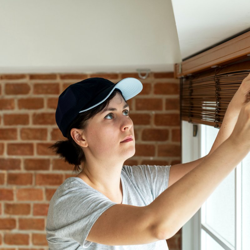 A female professional installer installing wooden window blinds