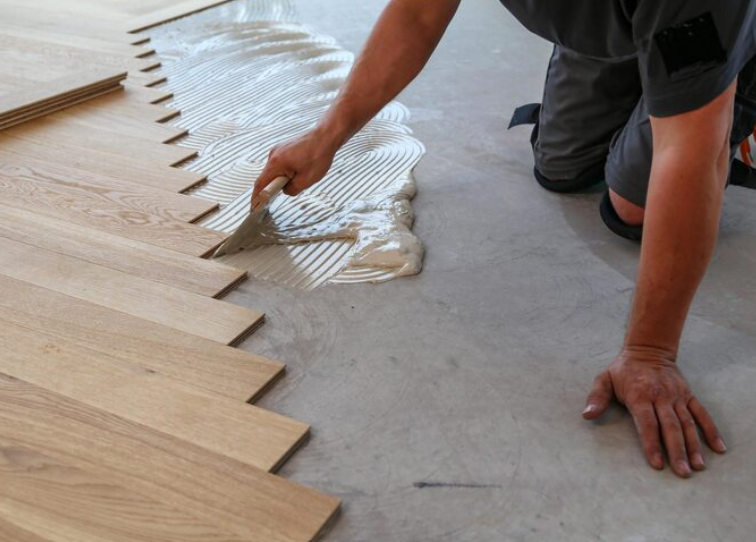 A male worker installing a wooden laminate flooring on his knees