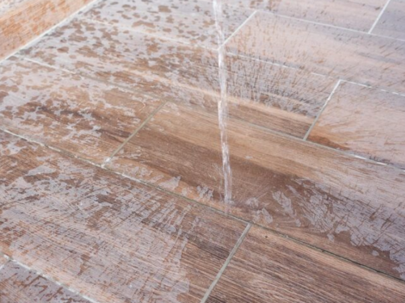Water splashes on wood-look tiles, showing texture and moisture resistance—ideal for kitchens, baths, or patios.
