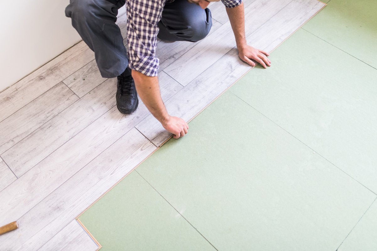 Worker processing a floor with bright laminated flooring boards
